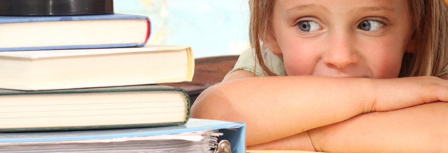 little girl looking at a stack of books