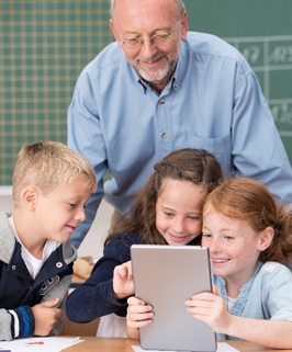 three students and a teacher looking at a tablet